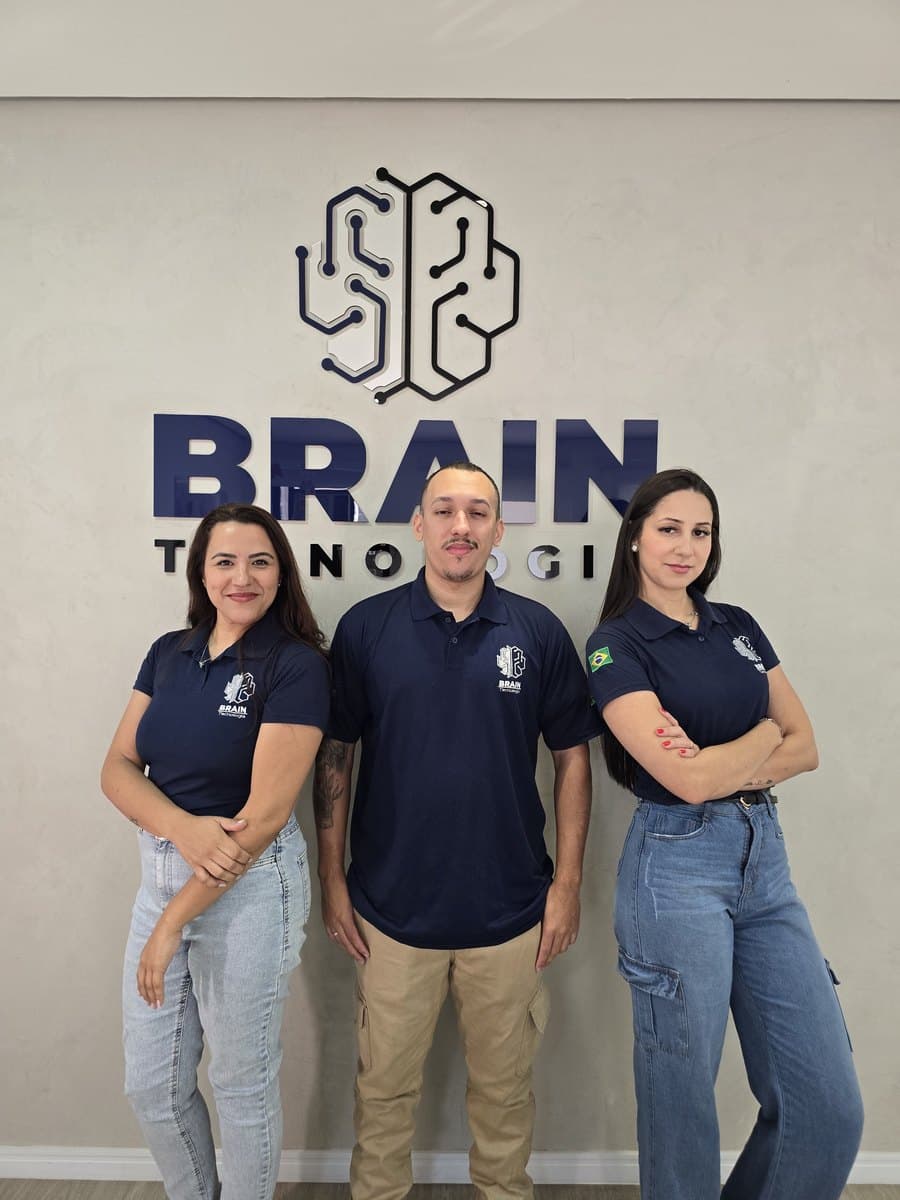 Colaboradores da Brain reunidos em frente à parede com a marca